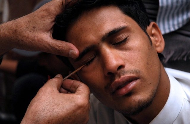 A Yemeni therapist applies Kohl to the eyes of a youth, in line with local tradition on the second day of the holy month of Ramadan at a Zaidi (Shiite) mosque in Sanaa's Old City on August 23, 2009.