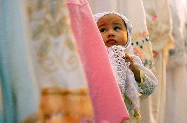 A child stands among worshippers attending prayers on the eve of the first day of the Islamic fasting month of Ramadan at Al Maerkaz Al Islami mosque in Makassar, South Sulawesi, Indonesia on August 21, 2009.