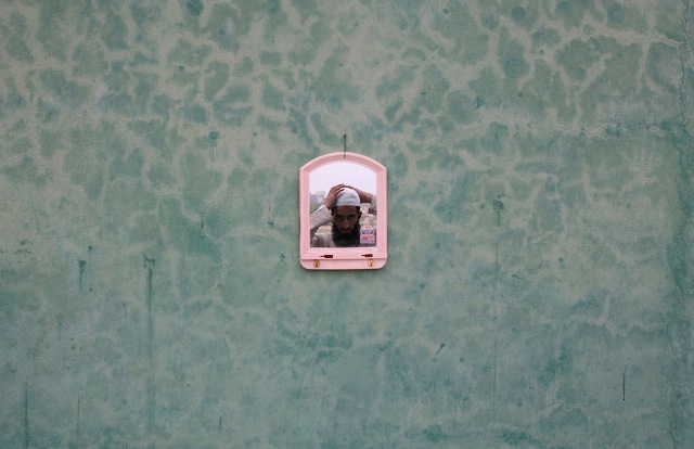 A Muslim man adjusts his cap in a mirror at a mosque on the first day of the holy month of Ramadan, in Jammu, Jammu and Kashmir, Indian-administered Kashmir on August 23, 2009.