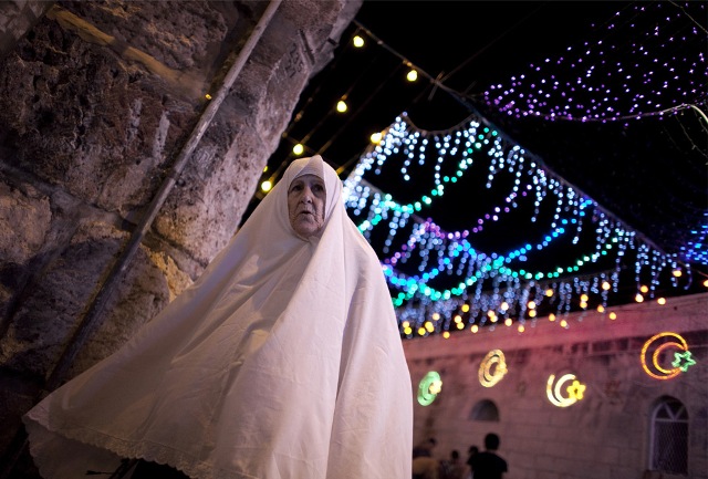 A Palestinian woman walks near the Lion's Gate in Jerusalem's old city where traditional festive lights are displayed ahead of the start of the Muslim holy month of Ramadan on August 20, 2009.