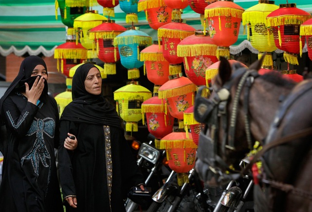 Egyptian women walk past paper lanterns used as decorations during Ramadan, on a street in downtown Cairo, Egypt on Wednesday, Aug. 19, 2009.