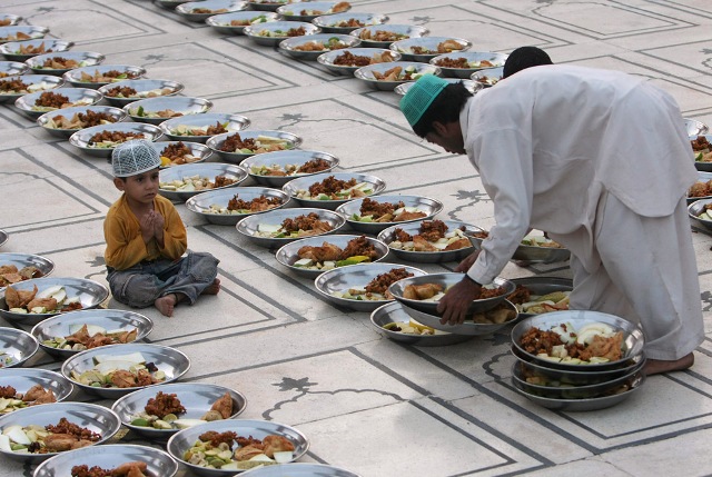 A Pakistani Muslim arranges food stuff for Iftar, a time to break the fast, on the first day of Ramadan, as a child looks on at a mosque in Karachi, Pakistan on Sunday, Aug. 23, 2009.