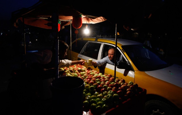 A taxi driver reaches for a glass of apple juice after sunset in Kabul, Afghanistan on Sunday Aug. 23, 2009. 